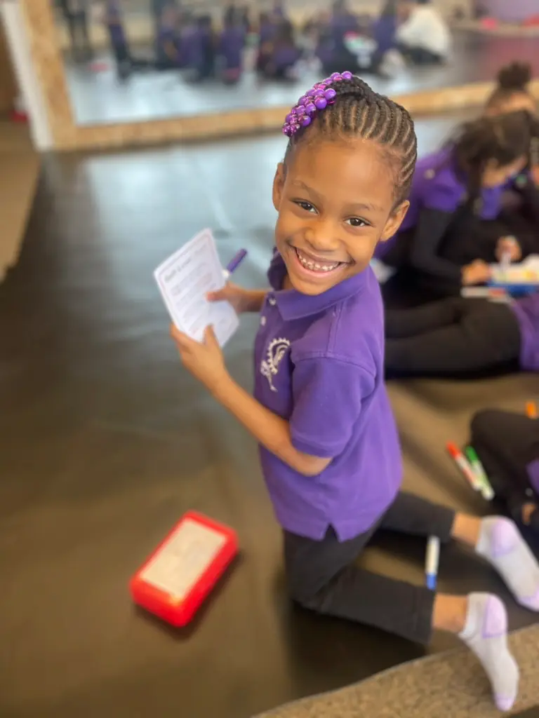 Happy student in purple shirt showing their work